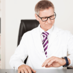 Doctor at desk looking at watch